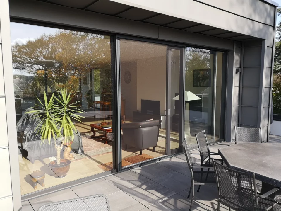 porte-moustiquaire-coulissante-sur-mesure-aluminium-feneko-sans-traverse-coloris-ral-9005-noire-toile-clearview-entrouverte-vue-exterieure-hdo-histoires-d-ombres-bruxelles-nivelles